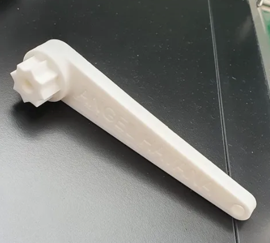 Cle nable plastique blanc tete octogonale vue laterale sur surface noire