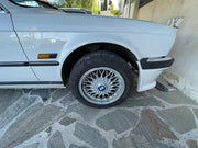Roue BMW E30 avec jante BBS et cache moyeu BMW bleu blanc installé vue rapprochée quartier avant