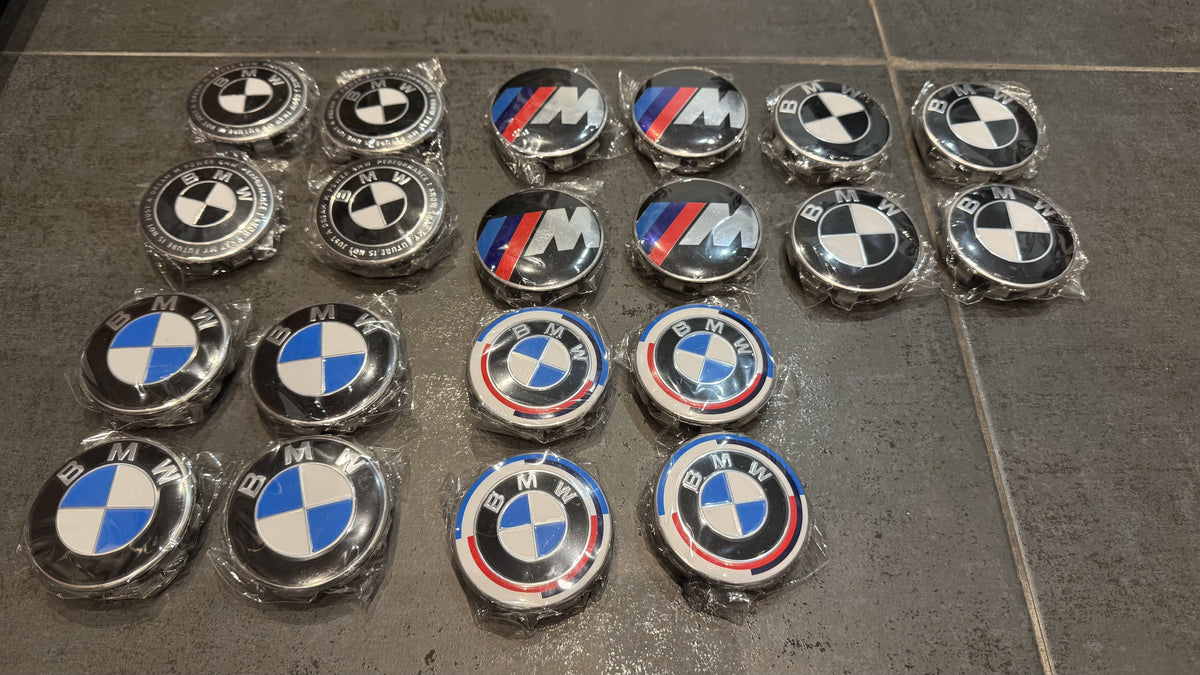 Collection insignes BMW pour caches moyeux incluant logos M Sport tricolores et BMW classiques emballés