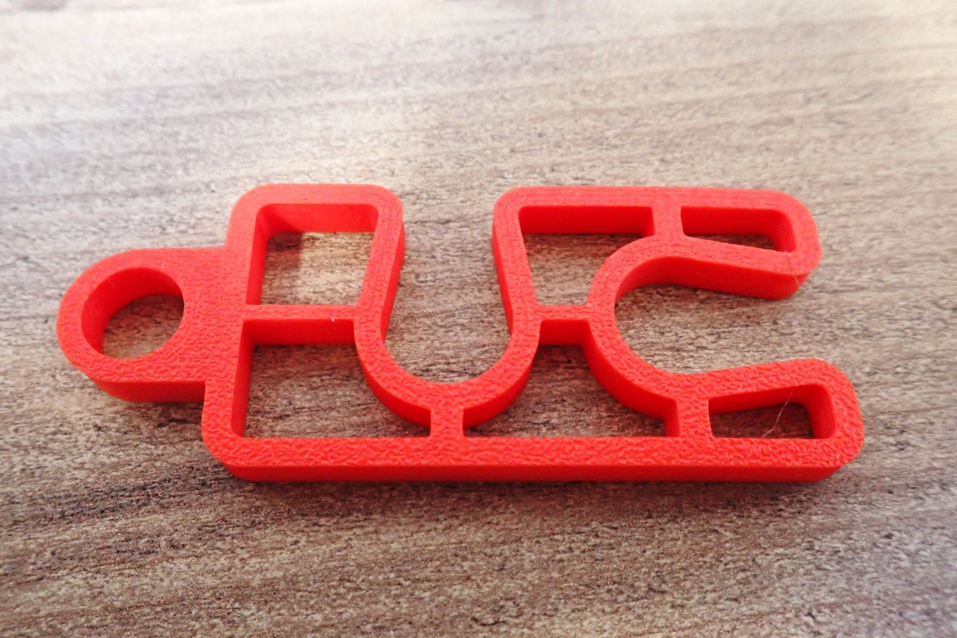 Clip double plat rouge isolé sur surface bois - vue dessus détail du produit en plongée