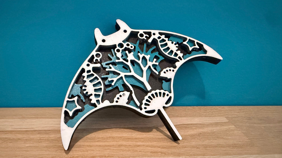 Décoration raie manta en bois blanc et turquoise posée sur une étagère